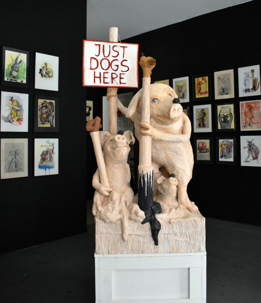 Sculptural pigs made from glued cardboard and mixed media, each wearing a dog’s snout over their noses.