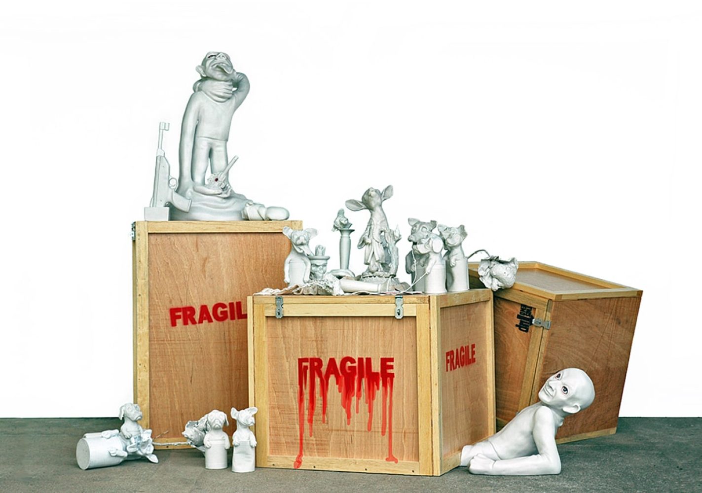 Installation of white sculptures arranged around wooden transport crates marked FRAGILE.
