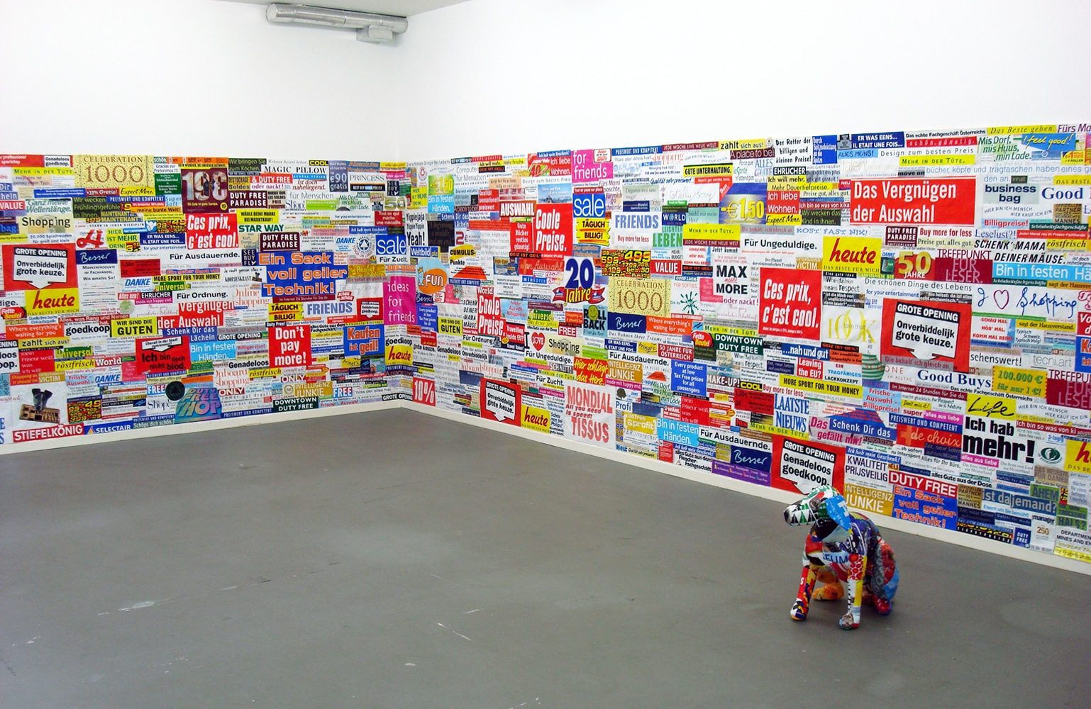 Installation view with a wall collage of advertising messages cut from plastic bags.
