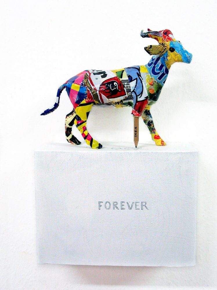 Deer sculpture covered in printed plastic bags, with one leg replaced by an IKEA pencil writing “Forever” on the box beneath it.