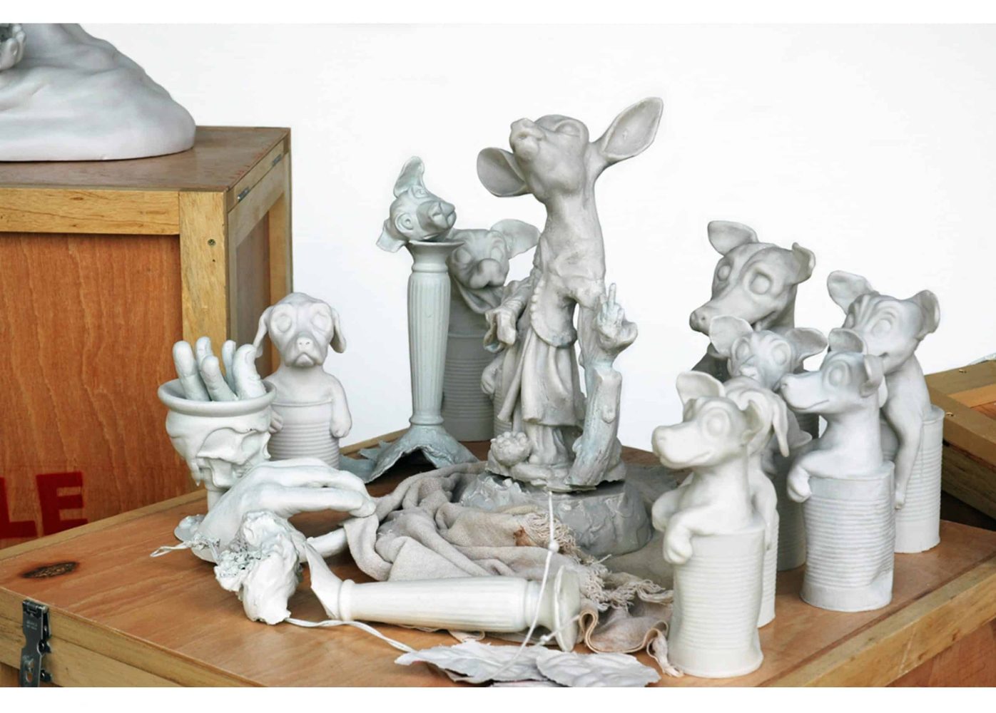 Installation detail with assorted sculptural objects and broken fragments of small dog figurines.