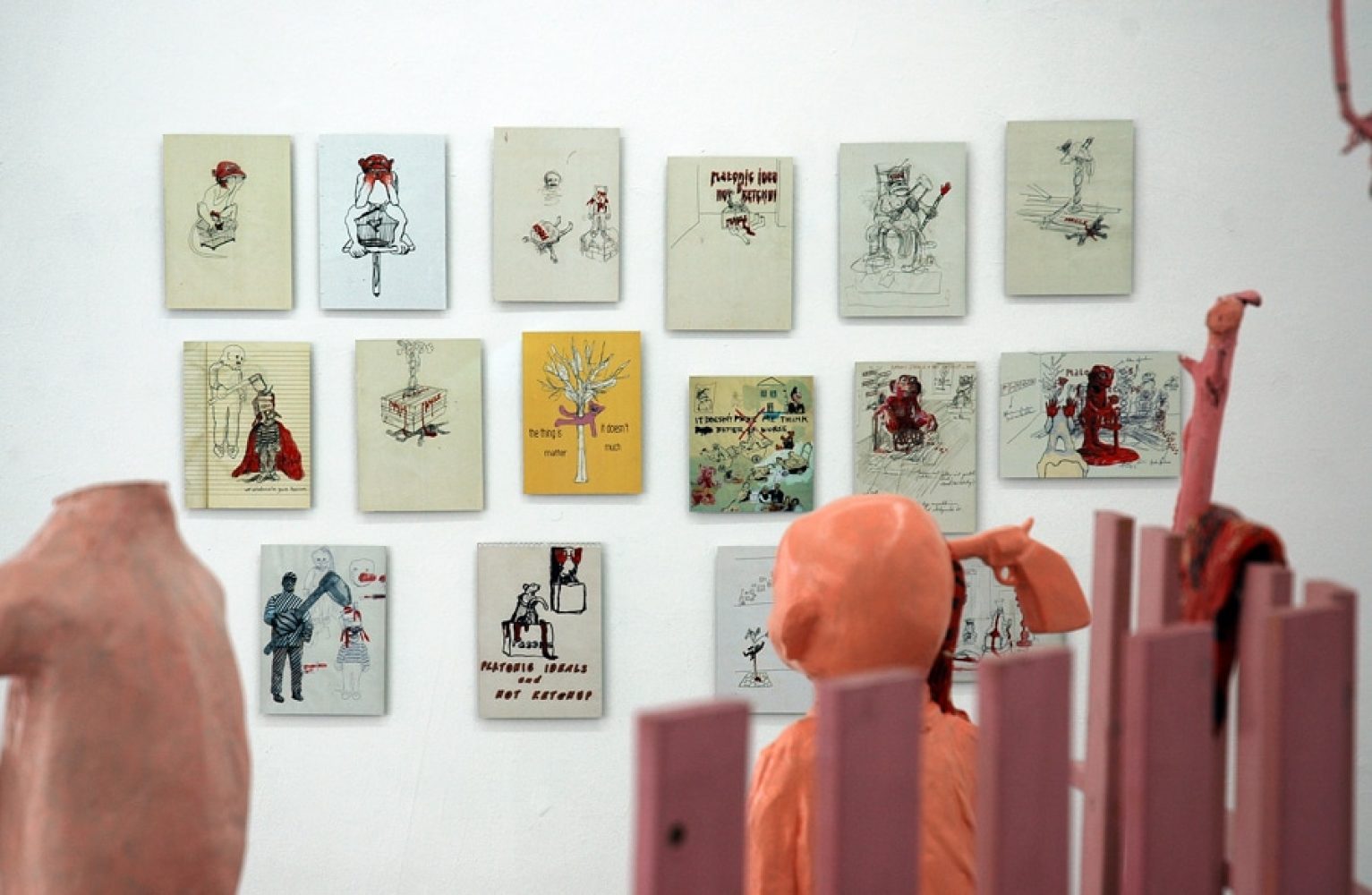 Installation view of Platonic Ideals & Hot Ketchup, with red and white sculptural figures and objects.