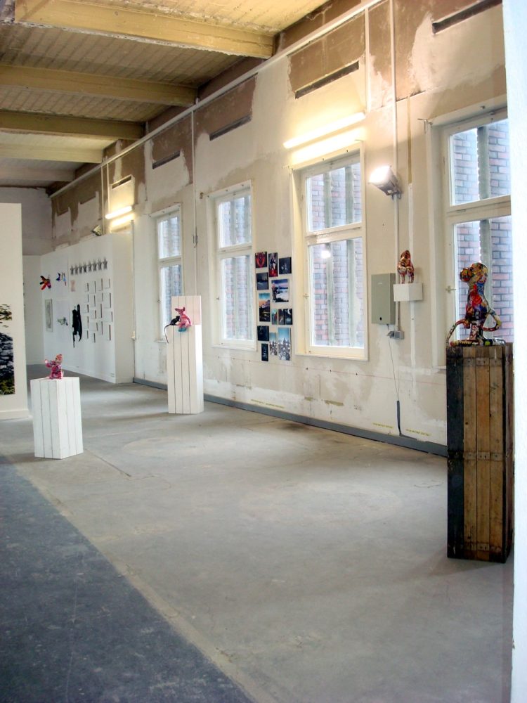 Installation view at Berliner Kunstsalon, with sculptural works displayed throughout a large industrial exhibition space.