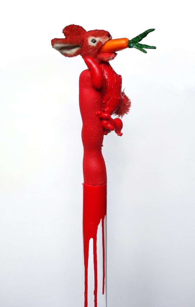 Tall red-painted skinned rabbit figure with a plush head and a carrot held in its mouth.
