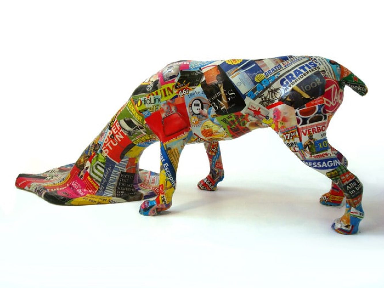 Side view of Scrap Dog, a dog-like sculptural figure with its head spreading across the floor.