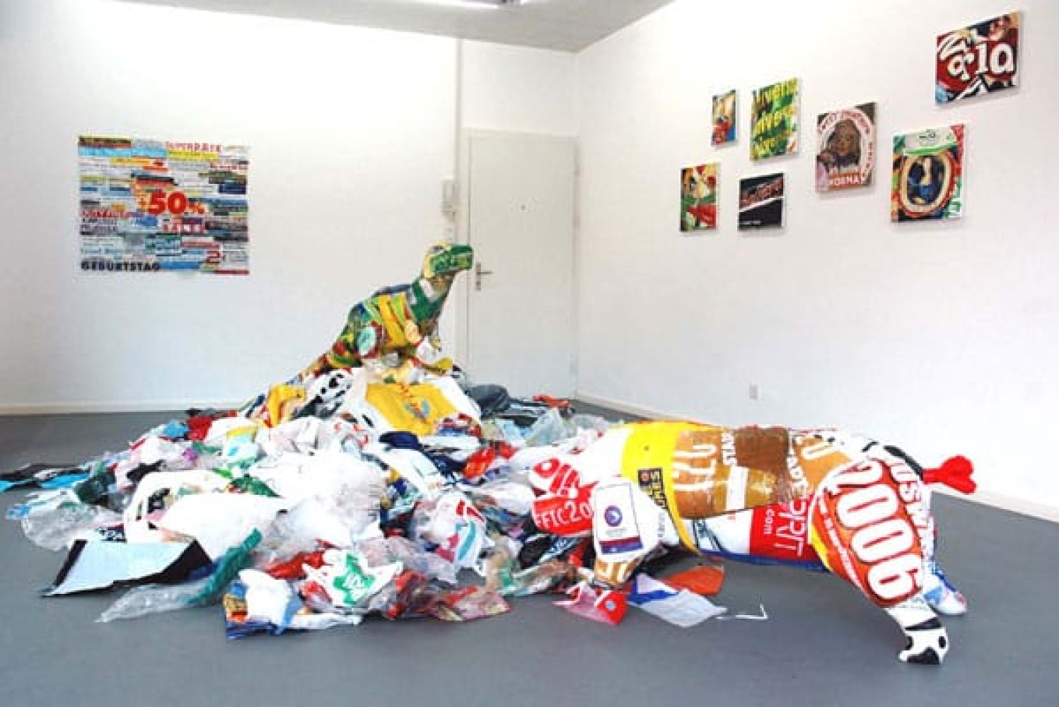 Dinosaur sculpture sewn from colourful plastic shopping bags standing on a large pile of discarded plastic bags.