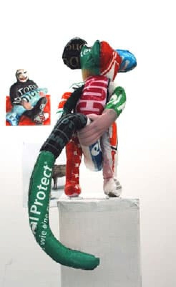 Standing figure sewn from colourful plastic shopping bags, holding its long tail in its hands.