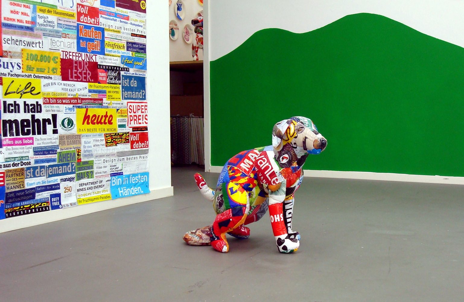 Installation detail with dog sculpture in front of a green wall.