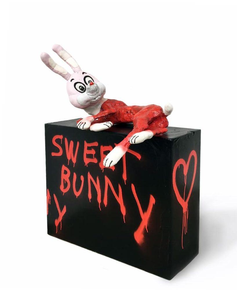 Black sculptural object with a white rabbit figure and the words “Sweet Bunny” in red.